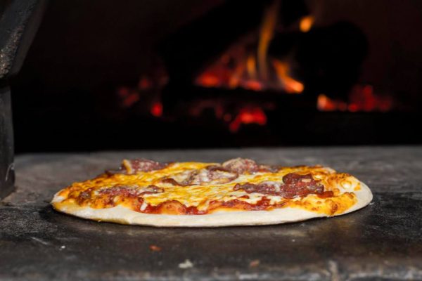 A pizza cooking in a woodfired oven.