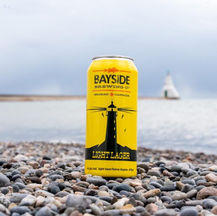 A yellow can of Lighthouse Light Lager on a rocky beach.