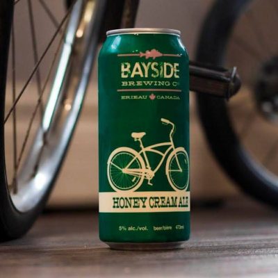 A green can of Honey Cream Ale in front of a bicycle.