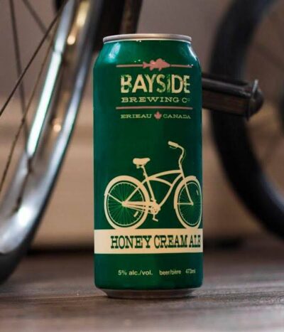 A green can of Honey Cream Ale in front of a bicycle.